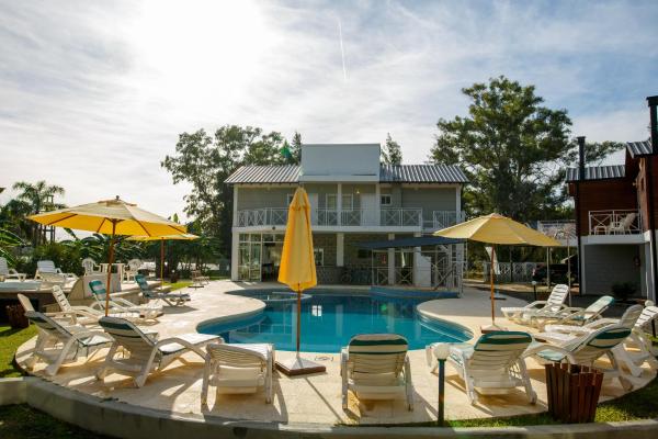 una piscina con sillas y sombrillas frente a un edificio en Placeres de la Costa en Gualeguaychú