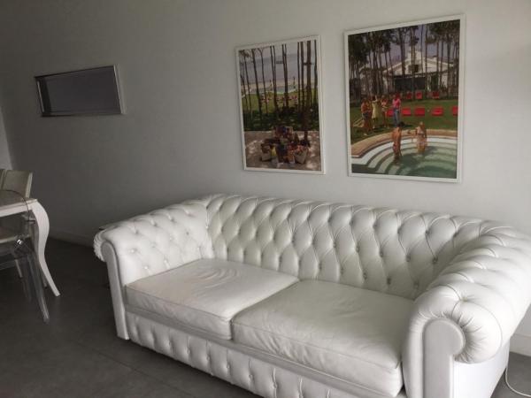 un sofá blanco en una sala de estar con pinturas en la pared en Yoo Deluxe Apartamento, en Punta del Este