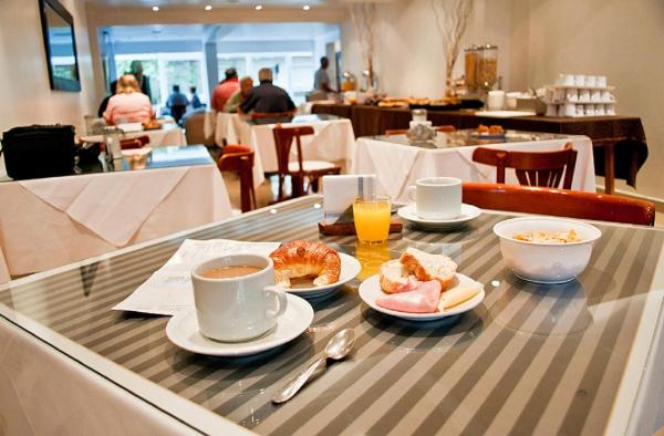 una mesa con platos de comida y tazas de café en Hotel Ortegal en Mar del Plata