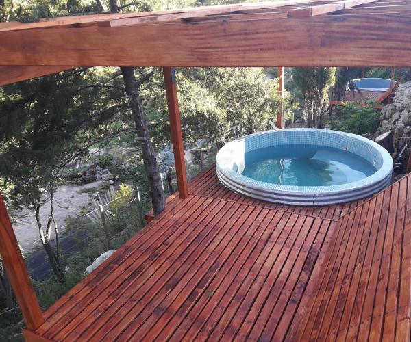 una terraza de madera con bañera de hidromasaje. en Cabañas y Toboganes Rancho la Ñata, en Mina Clavero