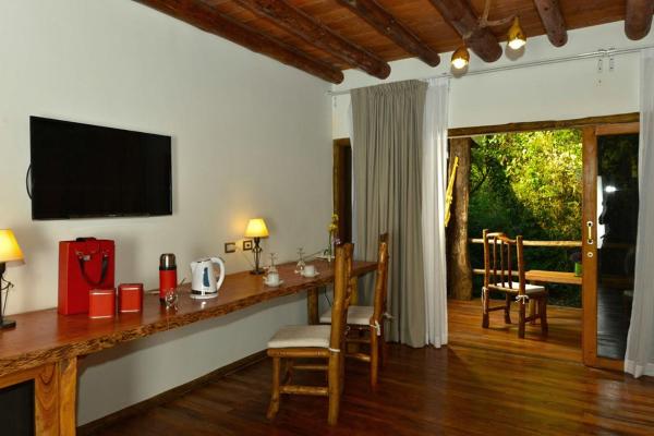 sala de estar con mesa y TV en la pared en La Aldea De La Selva Lodge en Puerto Iguazú