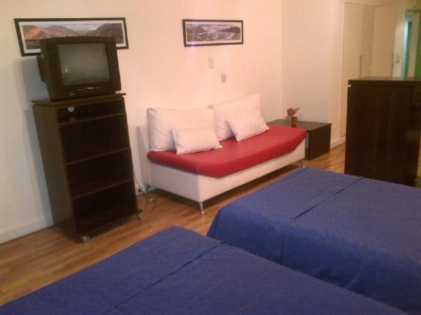 Habitación con cama, TV y sofá. en Córdoba Suites Recoleta en Buenos Aires