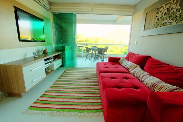 sala de estar con sofá rojo y TV en Villa das Ondas - Mariscal, en Bombinhas