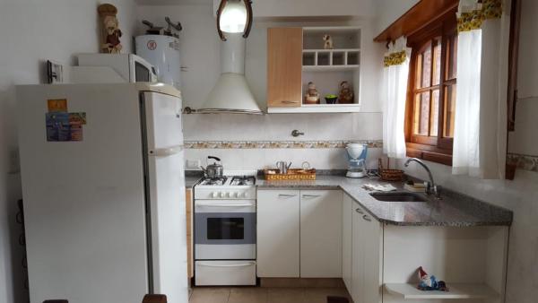una cocina con electrodomésticos blancos y nevera blanca en Saint Florentin Frente Al Mar en Villa Gesell