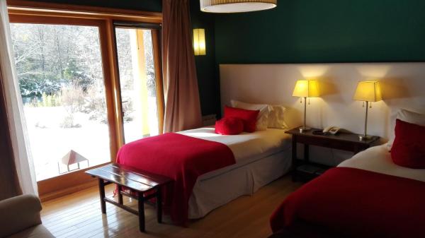 Habitación de hotel con 2 camas y ventana en Rio Hermoso Hotel De Montaña en San Martín de los Andes