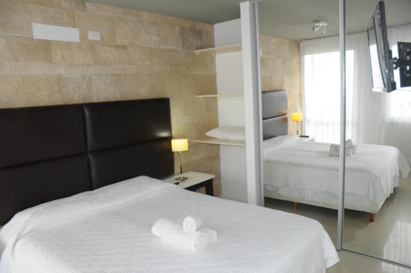 1 dormitorio con 2 camas y espejo en Linda Bay Beach & Resort Spa en Mar de las Pampas