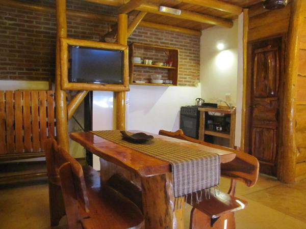 comedor con mesa de madera y TV en Loma Escondida Apart Cabañas & Spa en Villa Gesell