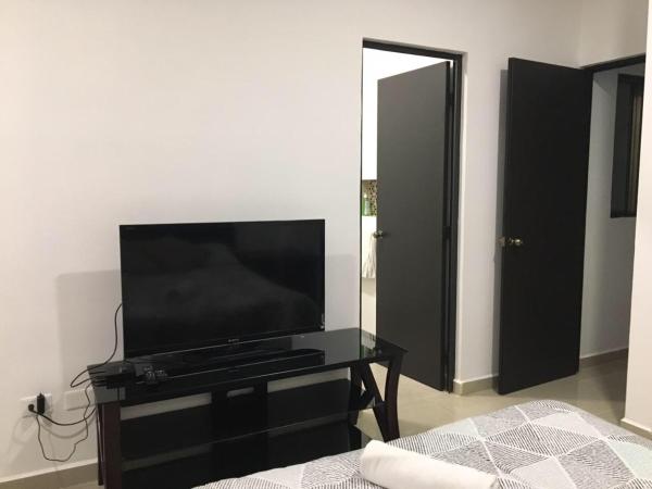 TV de pantalla plana en una cómoda negra en un dormitorio en Casa Caribe Vacacional, en Playa del Carmen