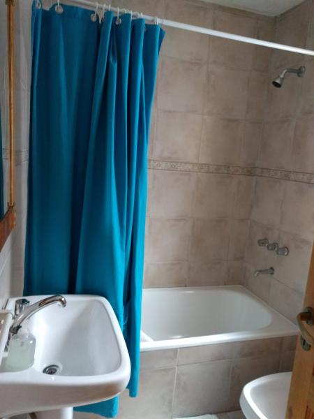 Baño con cortina de ducha azul junto a un lavabo en 845 Teniente Ramayón en San Martín de los Andes