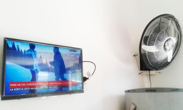 TV de pantalla plana y ventilador en la pared en Sol y Sombra en Villa Gesell