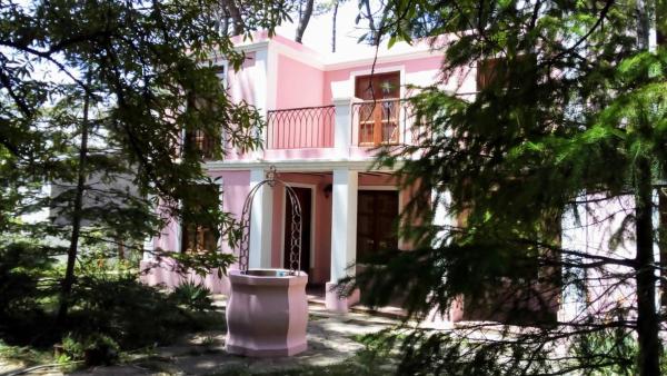 Casa rosa con balcón y árboles a marratxi en Villa Gesell