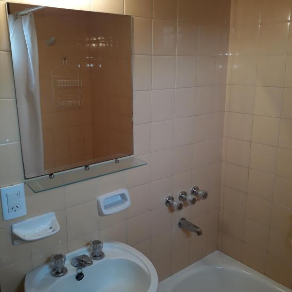 y baño con aseo y ducha con espejo.  en Departamentos Bezbel - Mariska en Villa Gesell
