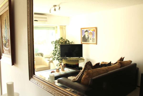 espejo en la sala de estar con sofá y TV en Apartamento en Punta del Este Playa Mansa, en Punta del Este