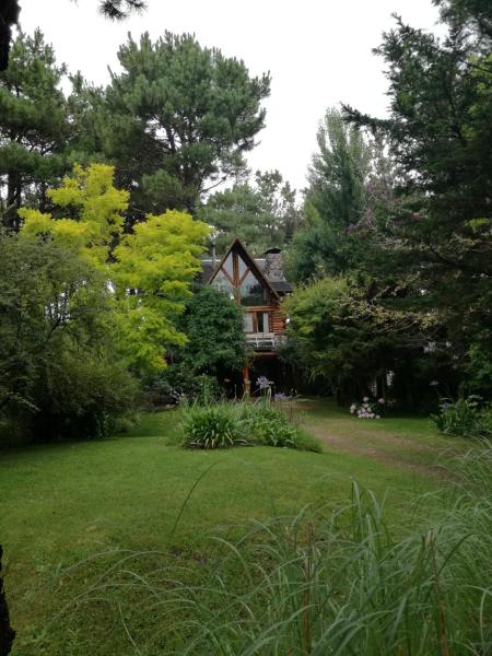 una casa en medio de un patio con árboles en Cabana de troncos Willow en Mar de les Pampas