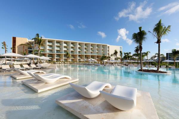 un complejo con piscina con sillas blancas y palmeras en Grand Palladium Costa Mujeres Resort & Spa - All Inclusive, en Cancún