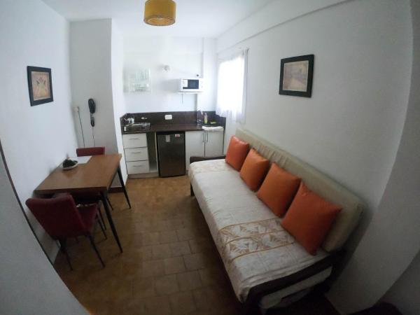 una sala de estar con un sofá con almohadas naranja en la Hostería Costa Azul de Villa Gesell