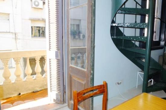 una silla de madera sentada junto a una puerta de cristal en Casa San Telmo 3100 en Buenos Aires