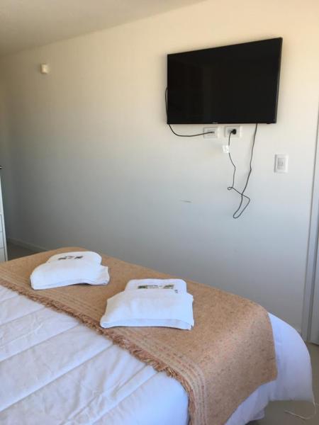 1 dormitorio con 1 cama y TV de pantalla plana en la pared en Mirasoles 20 en Las Gaviotas