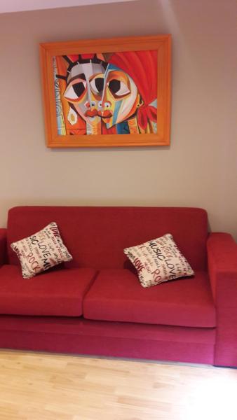 un sofá rojo con dos almohadas sentadas bajo una pintura en Los Perales en San Salvador de Jujuy