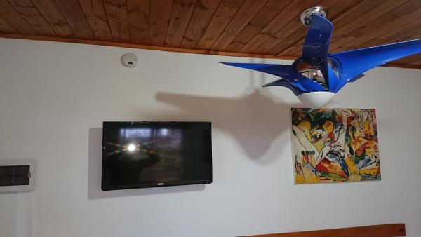 un ventilador de techo colgando de una pared con TV en Cabañas 57, en Villa Carlos Paz