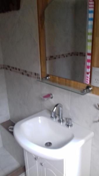 lavabo blanco en baño con espejo en Cabañas Villa Centauro en San Carlos de Bariloche