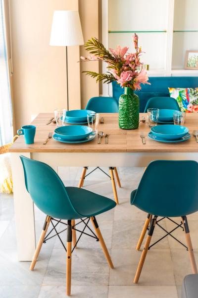 una mesa de madera con sillas azules y un jarrón de flores en HSH Suites Magdalena, en Sevilla