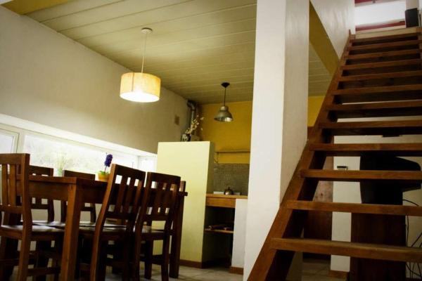 un comedor con mesa y sillas y una escalera en Cabañas Sottobosco, en Las Gaviotas