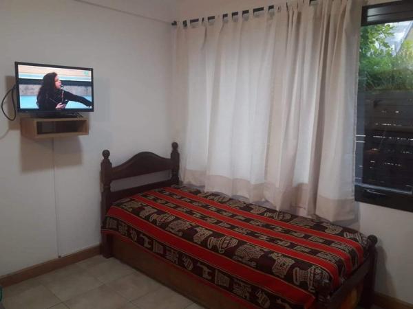 1 dormitorio con 1 cama y TV en la pared en Depto Centrico con pequeño jardin y parrilla en San Martín de los Andes