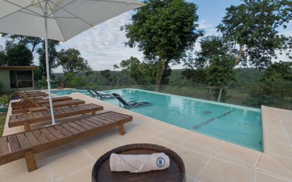 una piscina con bancos y sombrilla en Tupa Lodge en Puerto Iguazú