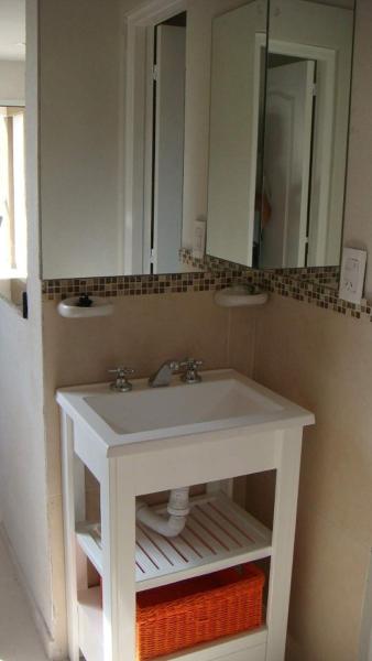 y baño con lavabo blanco y espejo. en Pinamar Alquilo Depto A 150 Mts Del Mar en Pinamar