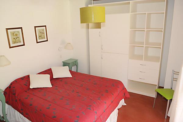 1 dormitorio con 1 cama roja y 1 silla verde en Cabañas San Dionisio en Mar de las Pampas