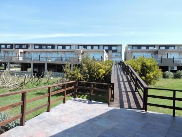 una pasarela de madera que conduce a un edificio con un edificio en Linda Bay Premium Resort en Mar de les Pampas
