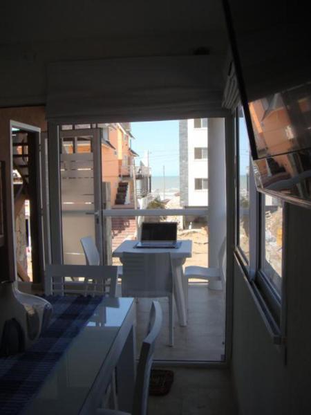 Habitación con vistas a un balcón con mesa y ventana. en Pinamar Alquilo Frente Al Mar en Ostende