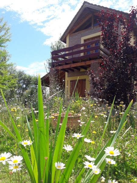 un jardín frente a una casa con flores en Cabañas Vientos del Sur, en Villa Yacanto