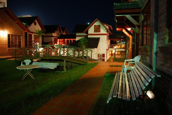 dos bancos y una mesa en un patio de noche en el Sol del Sur Gesell en Villa Gesell