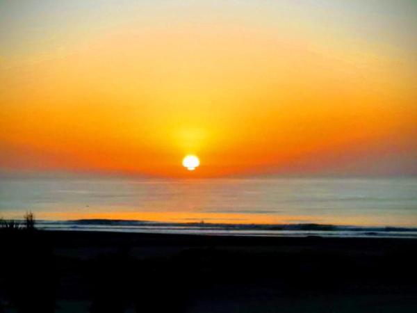una puesta de sol en la playa con el sol en el cielo en Altos Las Gaviotas 7, en Las Gaviotas