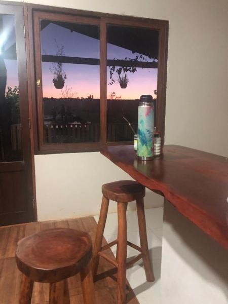 una mesa con dos taburetes y una ventana con vistas en La casa del Lago - The lake house ! en Puerto Iguazú