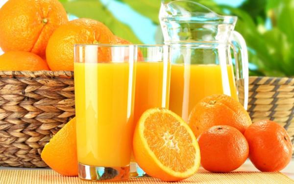 un vaso de zumo de naranja junto a una cesta de naranjas en Dos Mareas Apart - Piscina Climatizada Cubierta en Ostende