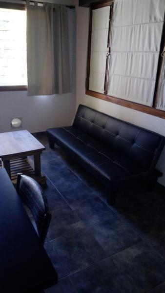 un salón con un sofá negro y una mesa en Pineta 4 y 7 de Villa Gesell