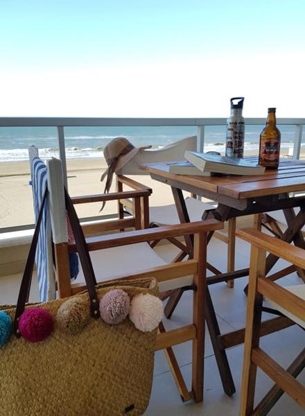 una mesa y sillas junto a una mesa y una playa en el 108 y El Mar de Villa Gesell