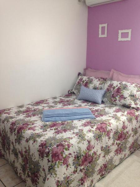 a bedroom with a bed with a floral bedspread at Charmoso apto com clima de casa em Canasvieiras in Florianópolis