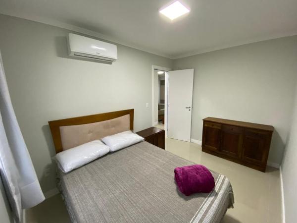 Dormitorio con cama con almohada morada en Edifício Florenza, en Bombinhas