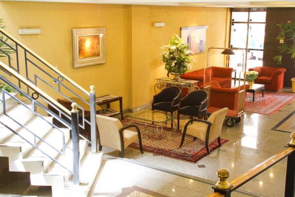 a lobby with chairs and a staircase in a building at Trevi Hotel e Business in Curitiba