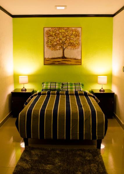 1 dormitorio con una pared verde, 1 cama y 2 lámparas en Casa Mar, en Playa del Carmen