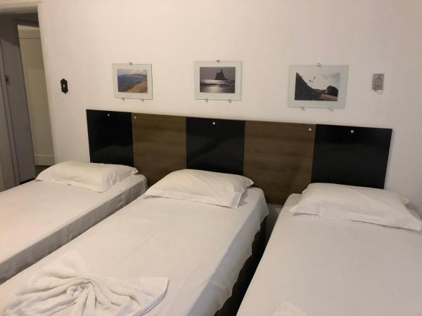 two twin beds in a room with three pictures on the wall at AP na Rua das Flores in Curitiba