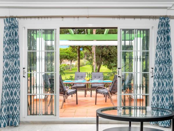 un porche cubierto con mesa y sillas en Holiday Home Los lomos de Cabopino, en Marbella