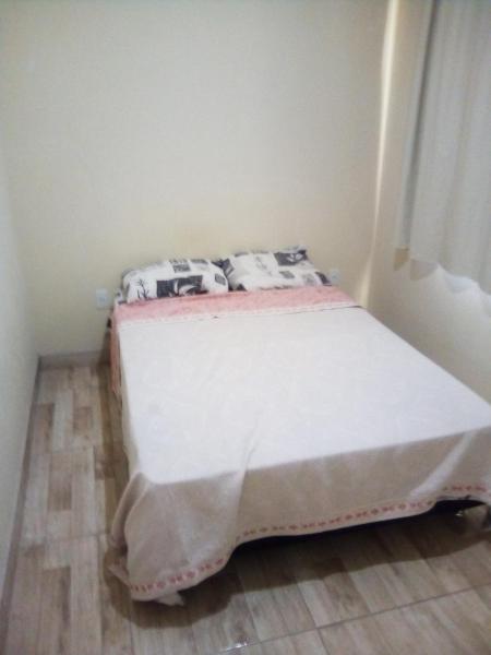 a small bedroom with a bed with white sheets at Casa no rio vermelho in Florianópolis