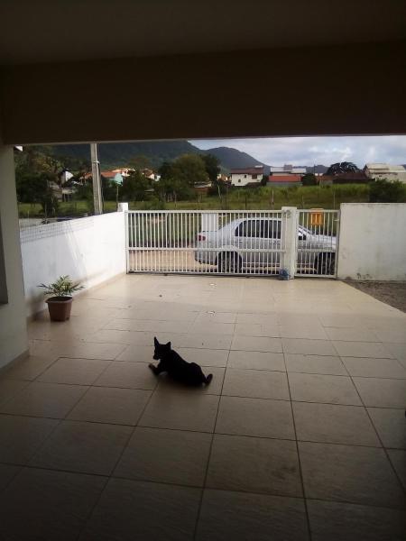 a black cat laying on the floor next to a fence at Casa no rio vermelho in Florianópolis