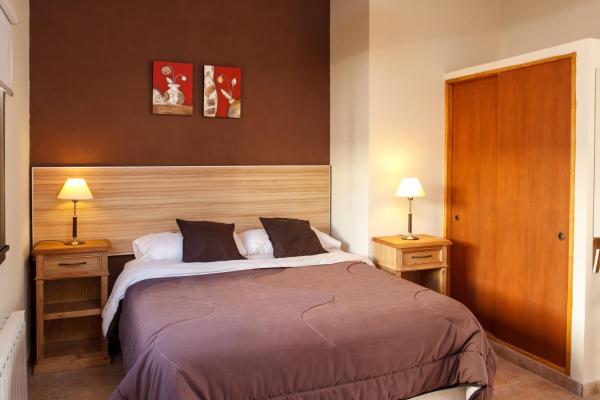 un dormitorio con una cama grande con dos mesas de noche y dos luces en el Alpemar Apart Hotel & Spa en Villa Gesell