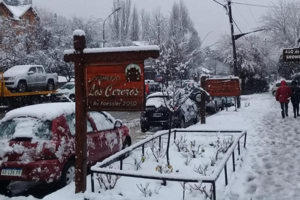 una calle cubierta de nieve con coches aparcados en Los Cerezos en San Martín de los Andes